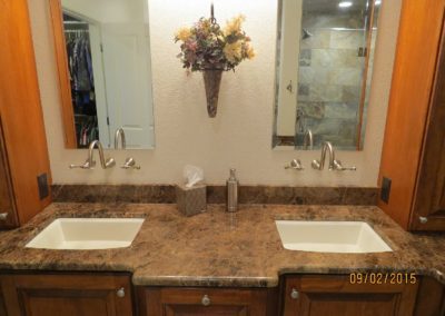 A full master bathroom remodel with granite counter, wooden cabinets, and lighting fixtures.