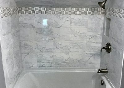 A large bath/shower combo with custom-tiled tiled walls.